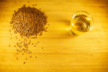 Flax seed handful, flaxseed oil in a glass on the table. Side view