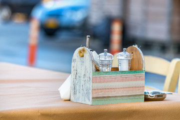 Salt and pepper grinders on a wooden table with paper tablecloth at a traditional greek tavern in...