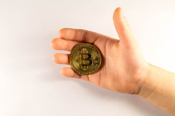 Naklejka na ściany i meble Bitcoin gold coin in the hands of a child. Crypto currency