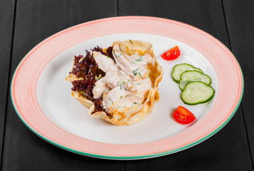 Stew chicken meat in sour cream sauce with greens in plate on dark background. Hot Meat Dishes. Top view, flat lay