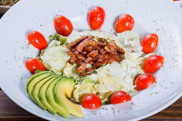 Hot salad with fried meat, lettuce, tomato and avocado on wooden table. Hot Meat Dishes. Top view