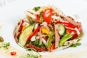 Fresh vegetable salad with cow tongue, spinach, green beans, tomatoes, sweet peppers, cabbage, mustard and dried tomatoes on plate on light wooden background. Healthy food. Top view