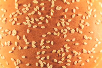 A large burger sprinkled with sesame top, cheese and salad. View from above. Close up