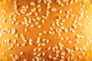 A large burger sprinkled with sesame top, cheese and salad. View from above. Close up