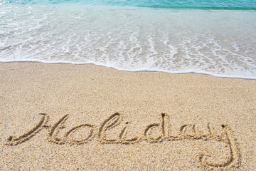 Fototapeta na wymiar Holiday inscription on a tropical sandy beach with waves and foam on a background. 