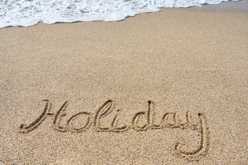 Holiday inscription on a tropical sandy beach with waves and foam on a background.    