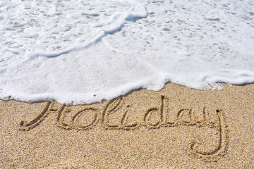 Holiday inscription on a tropical sandy beach with waves and foam on a background.    