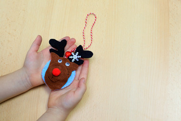 Child shows a felt Christmas tree toy. Child holds a Christmas tree toy in his hand. Easy winter crafts and activities for preschoolers