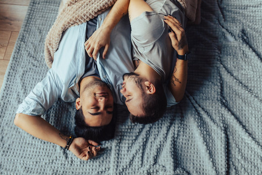 A homosexual couple relaxing in bed hugging and kissing each other. Happy moments of the day.