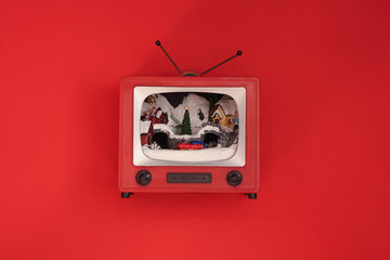 The red toy retro TV with Christmas decorations inside on a red background. Christmas holiday concept