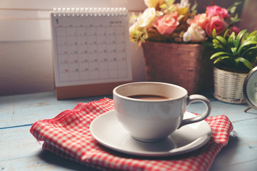 Cup of Coffee with Desktop Calendar 2019,clock and pot of rose flower on blue wooden desk.Calendar for Planner timetable,agenda appointment,organization,management each date,month and year.