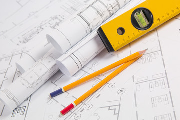 Pencils, spirit level and paper еngineering house drawings and blueprints.
