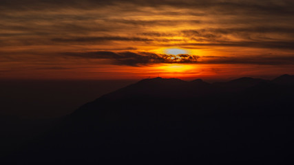 Fiery sunset from mountain peak in a cloudy evening. Fall season. Orobie mountains. Italian Alps