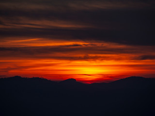 Fototapeta na wymiar Fiery sunset from mountain peak in a cloudy evening. Fall season. Orobie mountains. Italian Alps