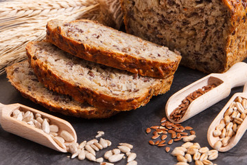 Wholegrain bread with ingredients for baking and ears of rye or wheat grain