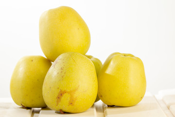Many green apples on a shelf. A white, wooden background.