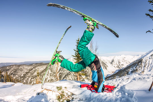 Freerider skier doing yoga stands on his head in skiing in the snowy mountains