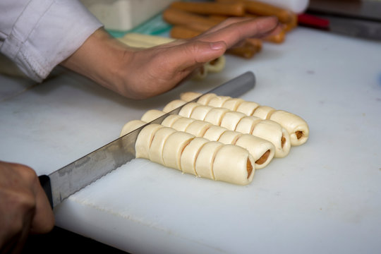 Sausages rolled in croissant dough baked cooling on metal rack.