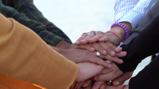 Arm stacked together one by one in unity and teamwork. Many hands getting together in the center of a circle. Close up outdoor shot. Many hands connecting in nature.