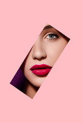 Beautiful woman face in pink paper frame. Plump red lips, blue eyes and clear skin. Fashion and...