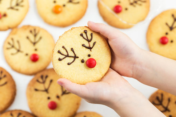Christmas deer cookies. Child holds cookies decorated with chocolate and candies
