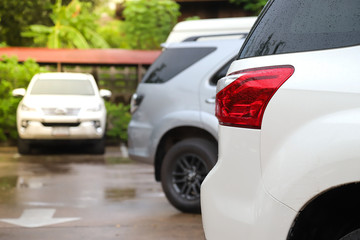 Closeup of rear side of white car parking in parking area after raining.