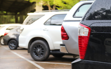 Fototapeta premium Closeup of rear side of black car parking in parking area after raining.