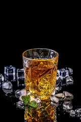 alcohol drink whiskey with ice and mint, glass of cognac on a black background. elite alcohol