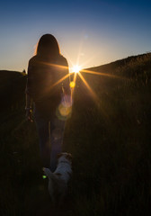 Happy celebrating winning success woman at sunset or sunrise standing elated with arms raised up above her head in celebration of having reached mountain top summit goal during hiking travel trek