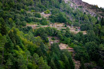 Stone terraces in mountain with two houses and forest