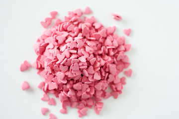 Many pink hearts candy sprinkles on white background