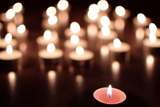 Pink tea light candles burning in darkness. Advent or memorial prayer candle flame.