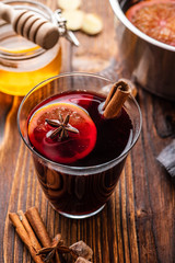 Hot mulled wine with spices, citrus and honey on woodern background. Copy space.
