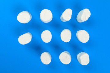 marshmallow laid out on blue paper background. pastel creative textured pattern.