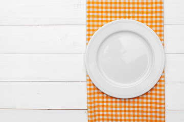 Empty plate and towel over wooden table background.