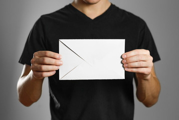 A man holding an envelope. Isolated on grey background.