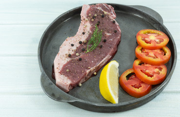 Grilled Striploin beef steaks in frying pan on white wood floor background props decoration Lemon, tomato, black pepper, Top view with copy space for your text..