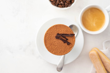 Tiramisu in a glass with coffee beans on white background. Copy space. Top view.