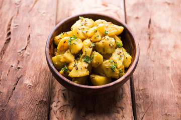 Jeera Aloo is a Indian main course dish which goes well with hot puris, chapatti, roti or dal. served in a bowl over moody background. selective focus