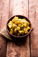 Jeera Aloo is a Indian main course dish which goes well with hot puris, chapatti, roti or dal. served in a bowl over moody background. selective focus