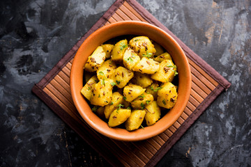 Jeera Aloo is a Indian main course dish which goes well with hot puris, chapatti, roti or dal. served in a bowl over moody background. selective focus