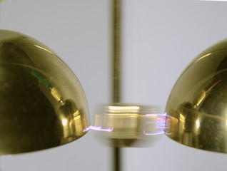Close up on a Franklin Bell setup, a small hammer swings between two bells, where the voltage...