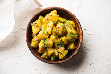 Jeera Aloo is a Indian main course dish which goes well with hot puris, chapatti, roti or dal. served in a bowl over moody background. selective focus