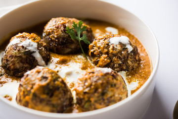 Malai Kofta is a Mughlai Speciality dish served in a bowl or pan over moody background. selective focus