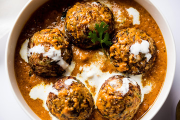 Malai Kofta is a Mughlai Speciality dish served in a bowl or pan over moody background. selective focus