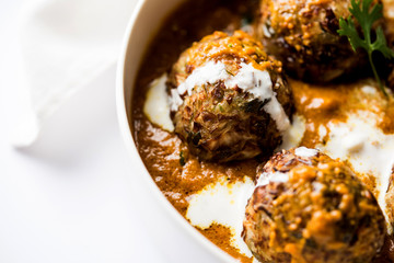 Malai Kofta is a Mughlai Speciality dish served in a bowl or pan over moody background. selective focus