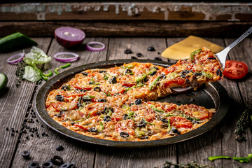 Hot pizza slice with melting cheese on a rustic wooden table. copy text recipe