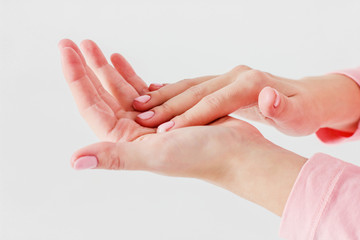 Beautiful delicate women's hands with pink manicure smudge caring cream hand massage isolated on gray background close up