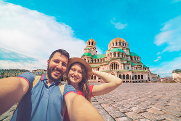 Fototapeta na wymiar Happy couple travelling in Sofia, Bulgaria, taking photo selfie in front of the main cathedral