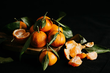 Ripe mandarins with leaves on a black background